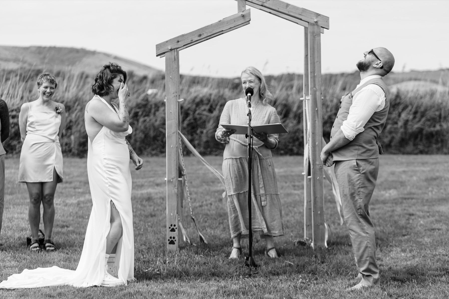 The couple laughing with the celebrant during their outdoor wedding ceremony