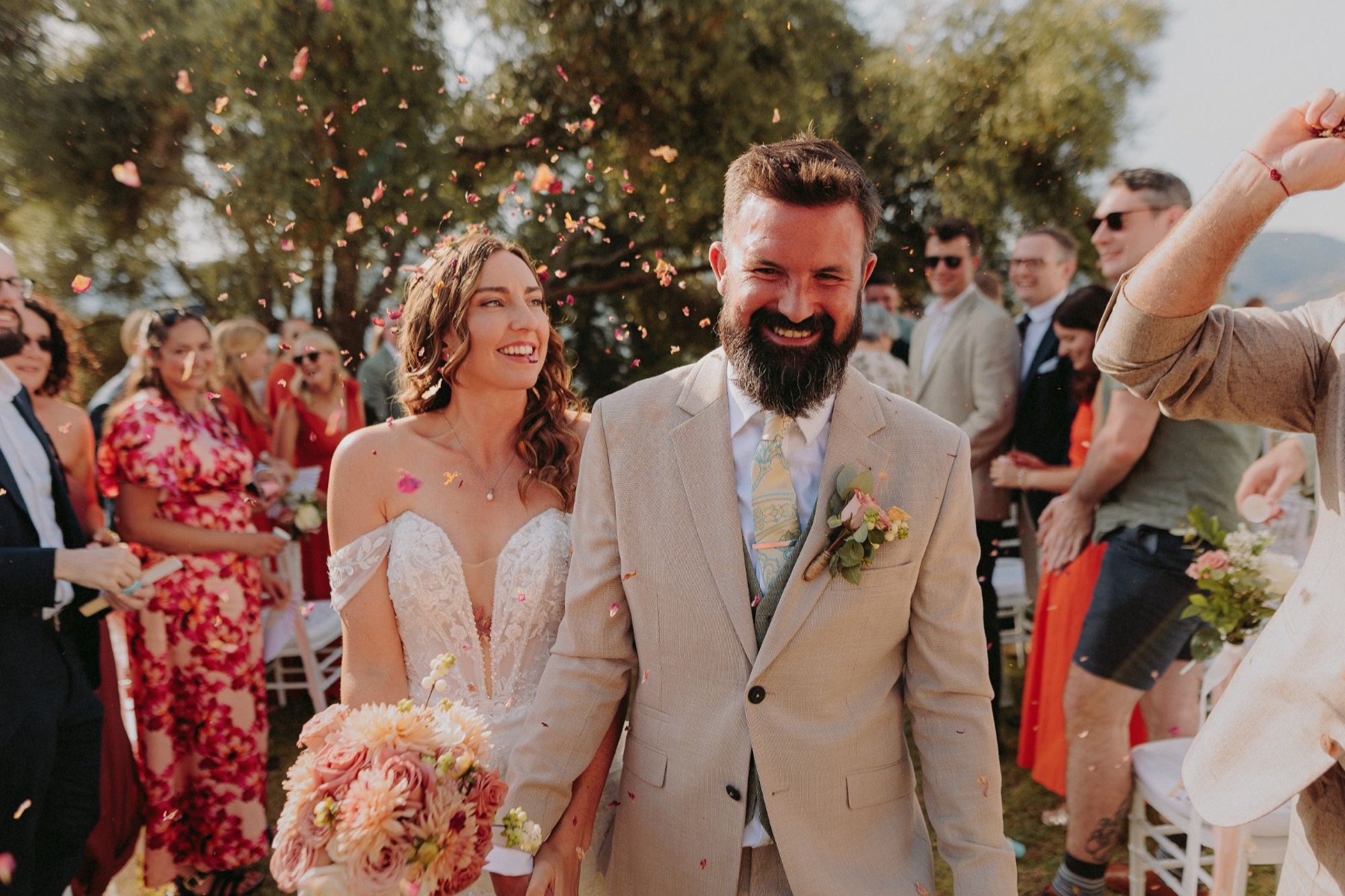 A newly married couple walking back down the aisle, laughing, as guests throw petal confetti