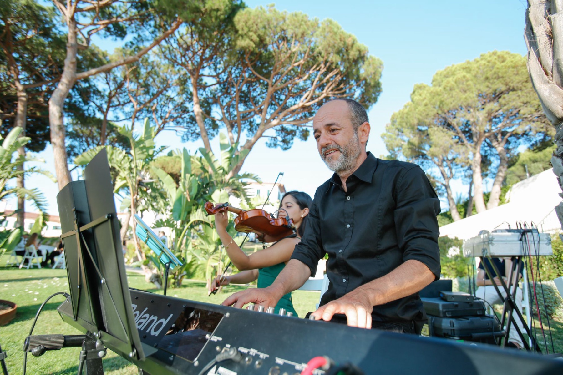 Musicians playing keyboard and violin at an outdoor wedding